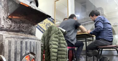 People sit next to a stove in a coffeehouse, in Ardahan, northeastern Turkey, Aug. 5, 2022. (AA PHOTO)