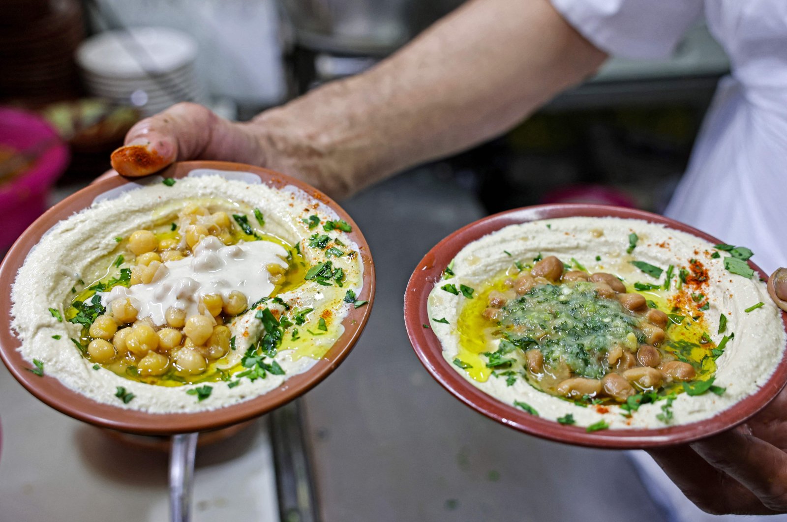 A cook prepares to serve plates of hummus and fava beans to be served to clients at a restaurant in the Old City of Jerusalem, occupied Palestine, July 26, 2022. (AFP Photo)