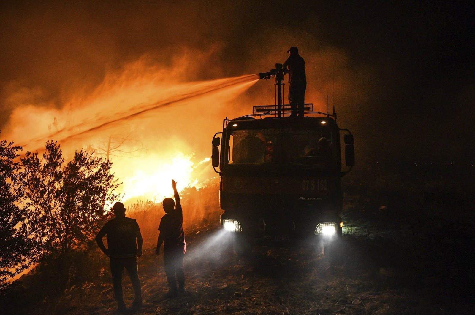 Firefighters pour water as they try to get the fire under control in Kirli village near the town of Manavgat, in Antalya province, Turkey, July 30, 2021. (AP Photo)