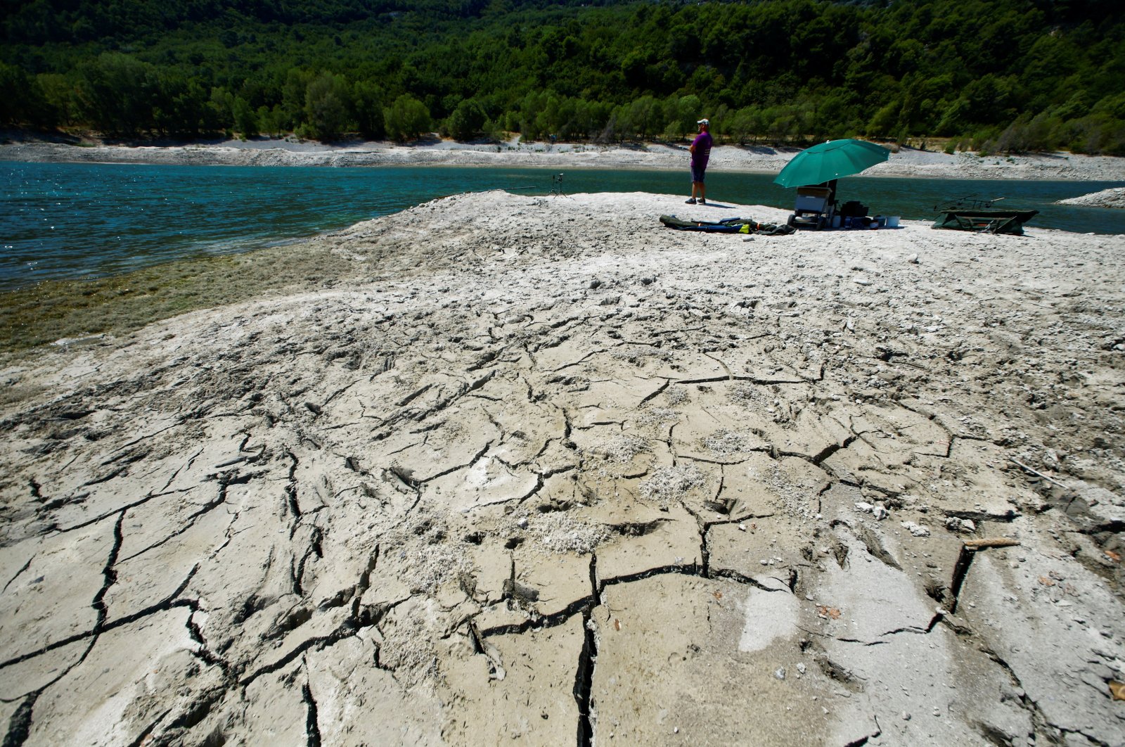 A fisherman is seen on cracked and dry earth of the banks of Le Broc lake, as a historical drought hits France, Aug. 5, 2022. (Reuters Photo)
