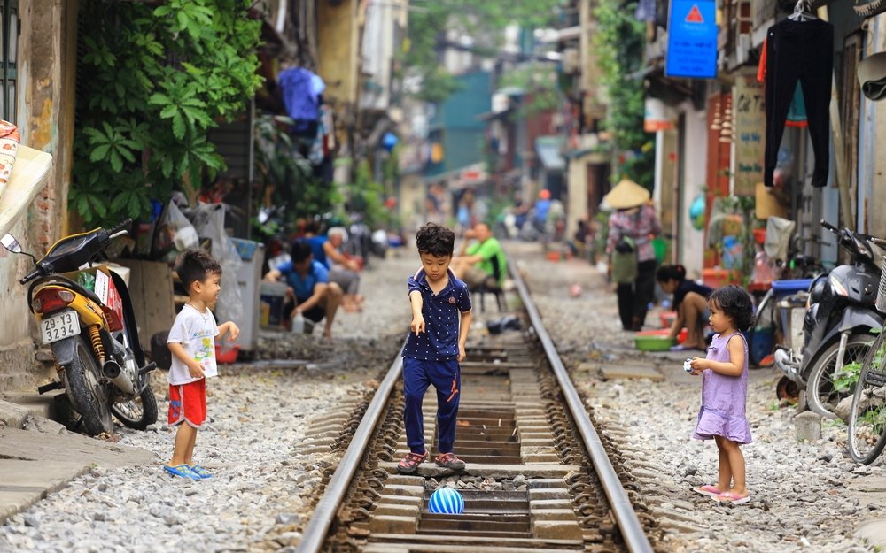 Anak-anak bermain di rel kereta api yang berjalan di sepanjang jalan sempit dengan rumah-rumah di Hanoi, Vietnam, 1 Mei 2017. (Foto Shutterstock)
