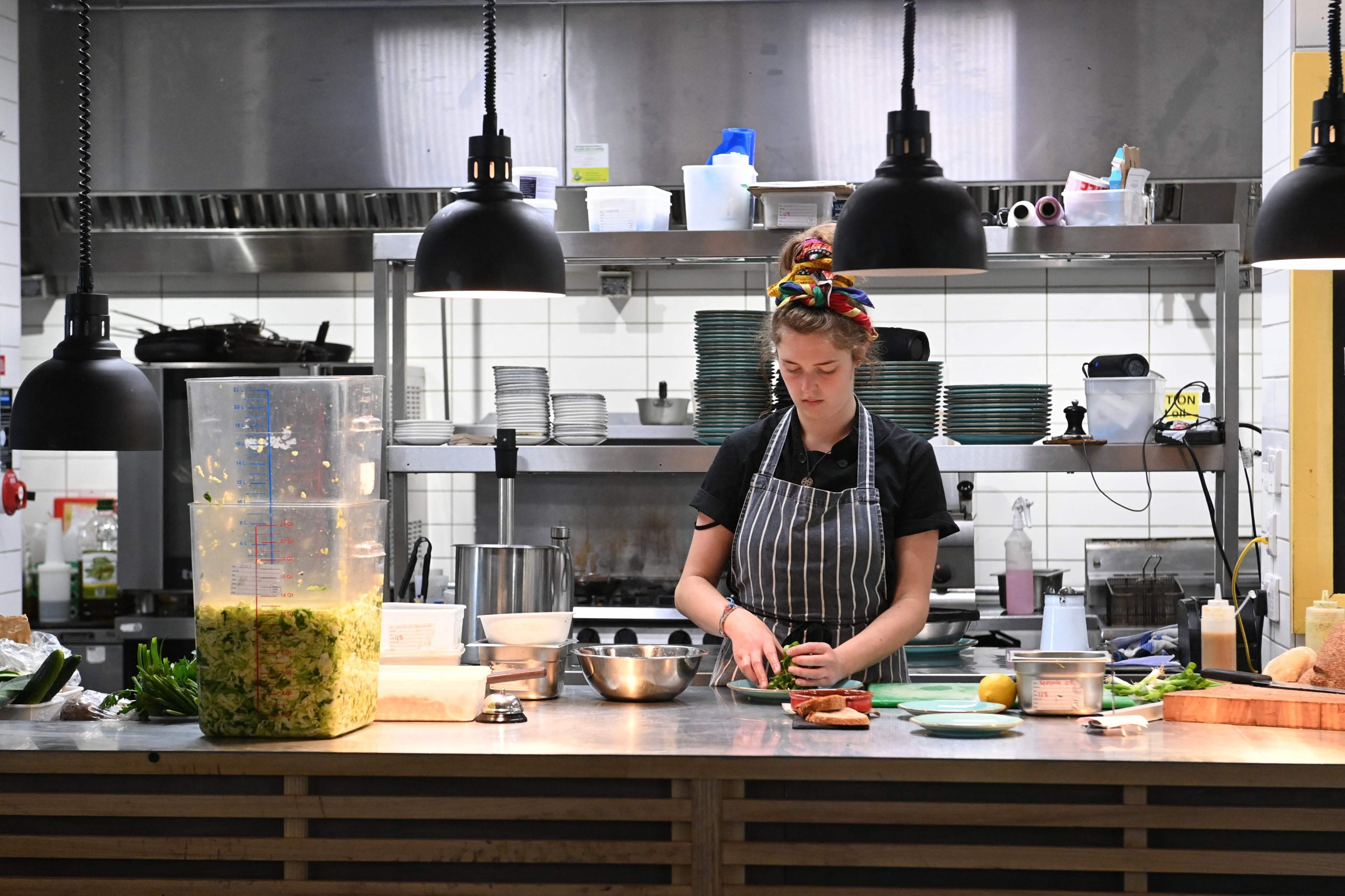 Seorang anggota staf menyiapkan makanan di restoran The Canteen di Bristol, Inggris, 3 Agustus 2022. (AFP Photo)