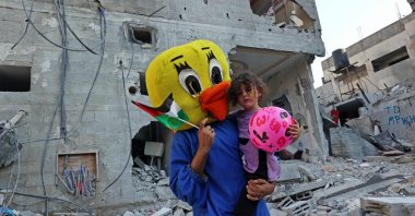 A Palestinian clown carries a child during a show amid the rubble of a building destroyed in the latest round of fighting between Israel and Palestinian militants, in Rafah in the southern Gaza Strip, Aug. 9, 2022. (AFP Photo)