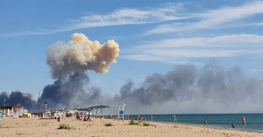 Rising smoke can be seen from the beach at Saky after explosions were heard from the direction of a Russian military airbase near Novofedorivka, Crimea, Ukraine, Aug. 9, 2022. (UGC via AP)