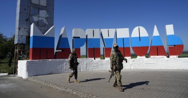 Russian soldiers walk past a repainted city name in the colors of the Russian flag at the entrance of Mariupol, on the territory which is under the Government of the Donetsk People&#039;s Republic control, eastern Ukraine, June 12, 2022. (AP Photo)