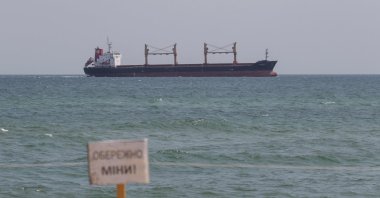 A warning sign that reads &quot;Caution! Mines!&quot; is seen as the Liberian-flagged bulk carrier Osprey S arrives near the port in Chornomorsk after restarting grain export, Ukraine, Aug. 10, 2022. (Reuters Photo)