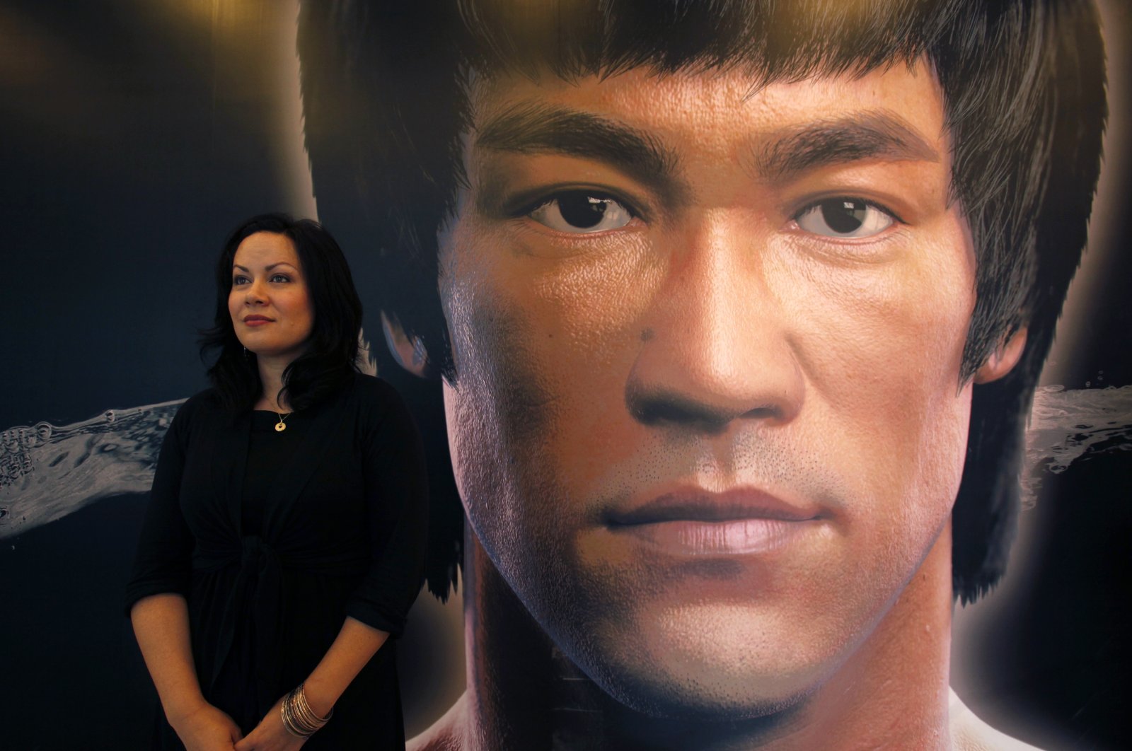 Shannon Lee, daughter of the late kung fu legend Bruce Lee, poses in front of a portrait of her father at the Hong Kong Heritage Museum, July 18, 2013. (REUTERS)