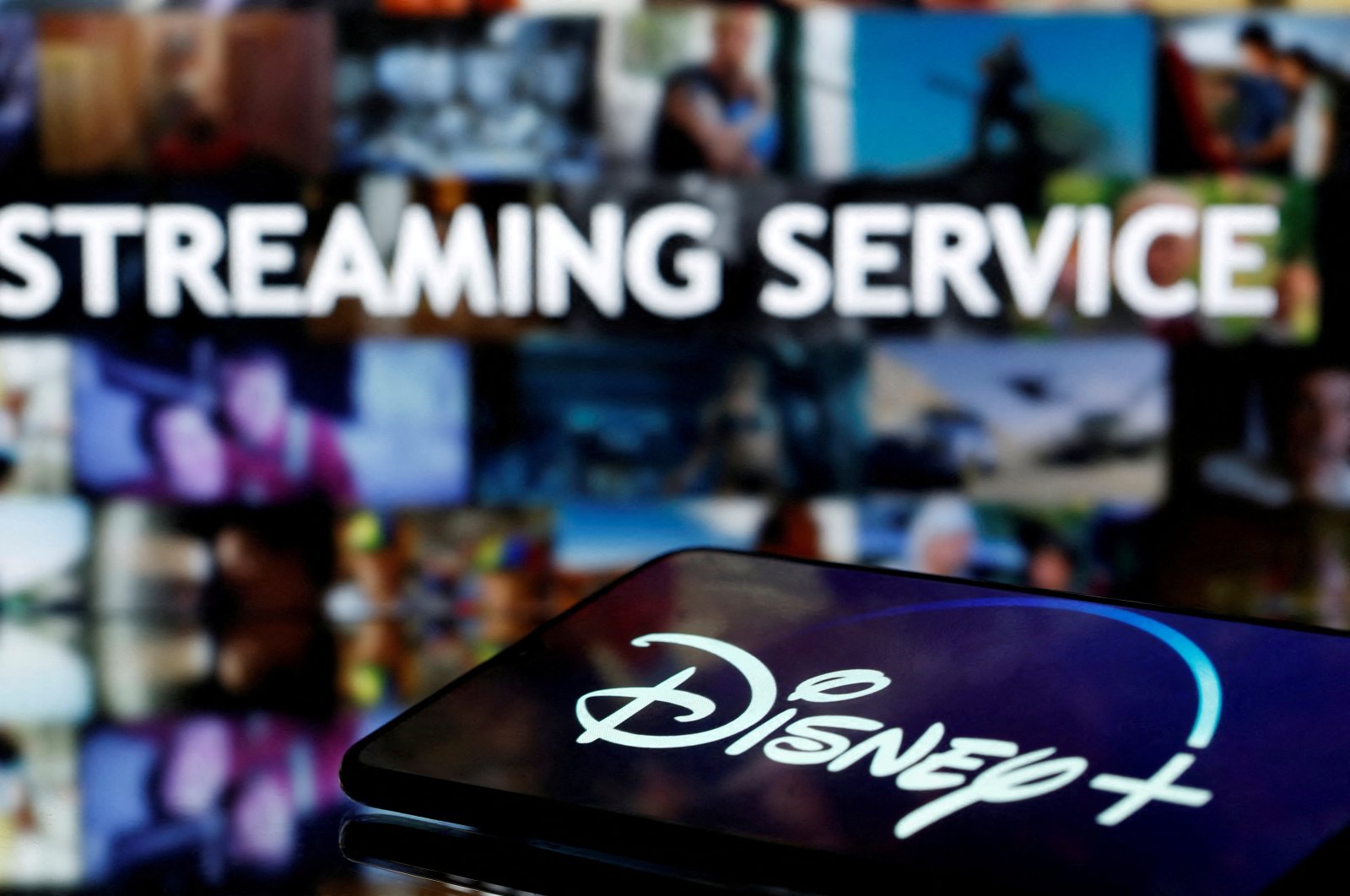 A smartphone screen showing the &quot;Disney &quot; logo is seen in front of the words &quot;streaming service,&quot; March 24, 2020. (Reuters Photo)