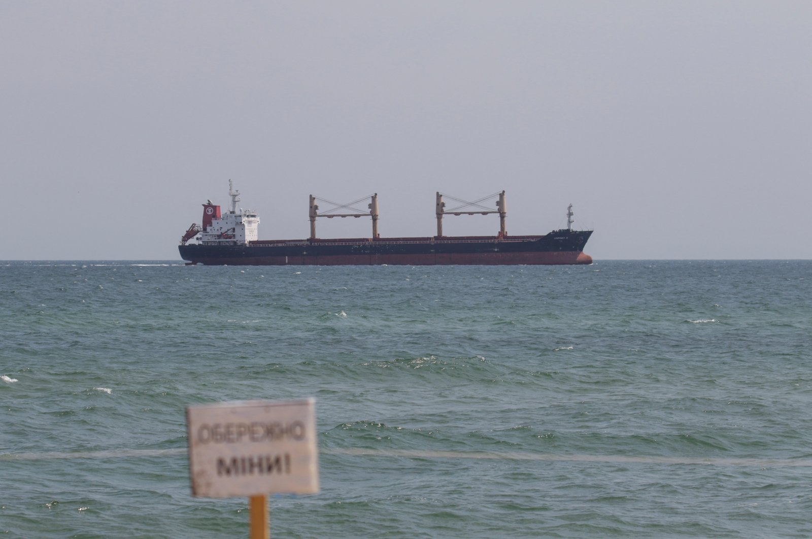 A warning sign that reads &quot;Caution! Mines!&quot; is seen as the Liberian-flagged bulk carrier Osprey S arrives near the port in Chornomorsk after restarting grain export, Ukraine, Aug. 10, 2022. (Reuters Photo)