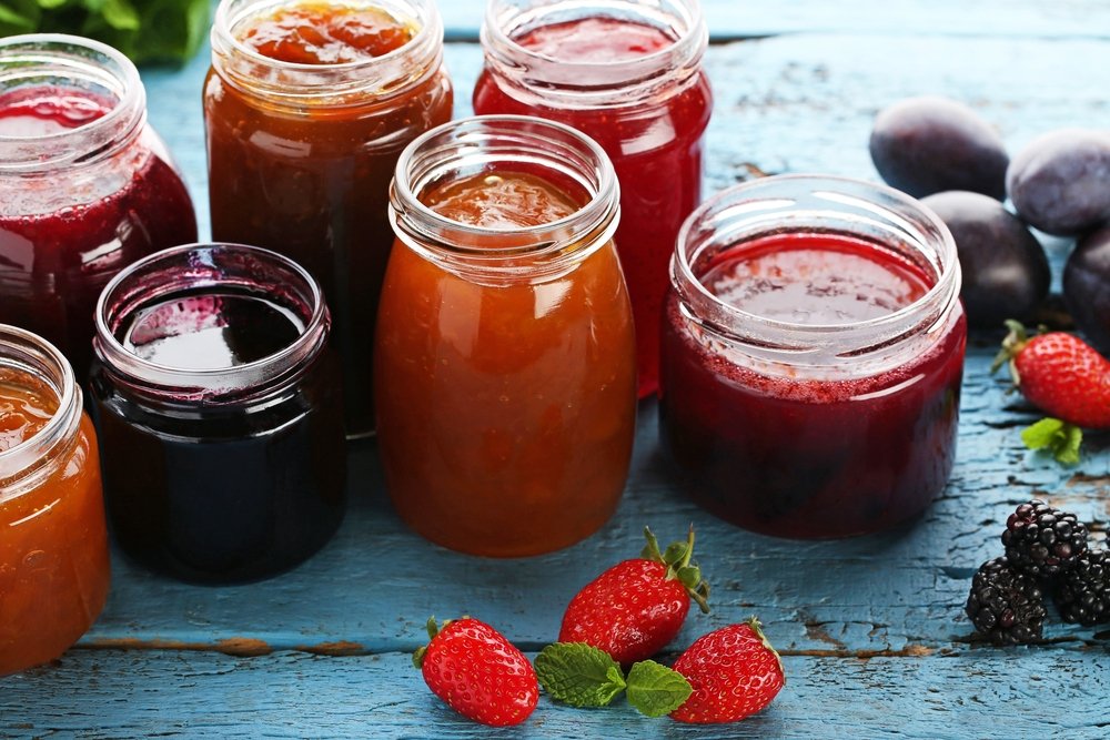 Glass jars with different kinds of jam and berries on wooden table. (Shutterstock Photo)