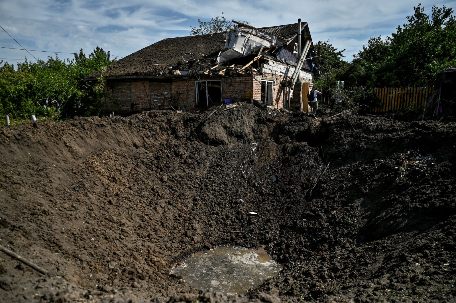 A man stands near a crater left by a Russian missile strike in the settlement of Kushuhum, in Zaporizhzhia region, Ukraine, Aug. 10, 2022. (Reuters Photo)