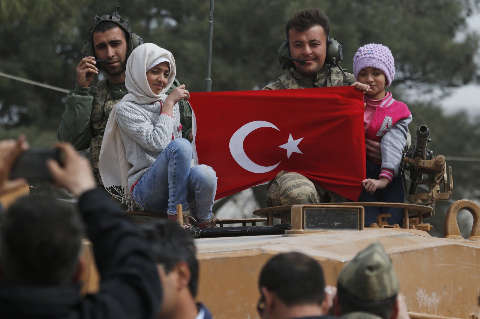 Turkish soldiers atop a tank pose for pictures with Syrian children holding a Turkish flag, during a Turkish government-organized media tour, in the northwestern city of Afrin, Syria. (AP Photo)