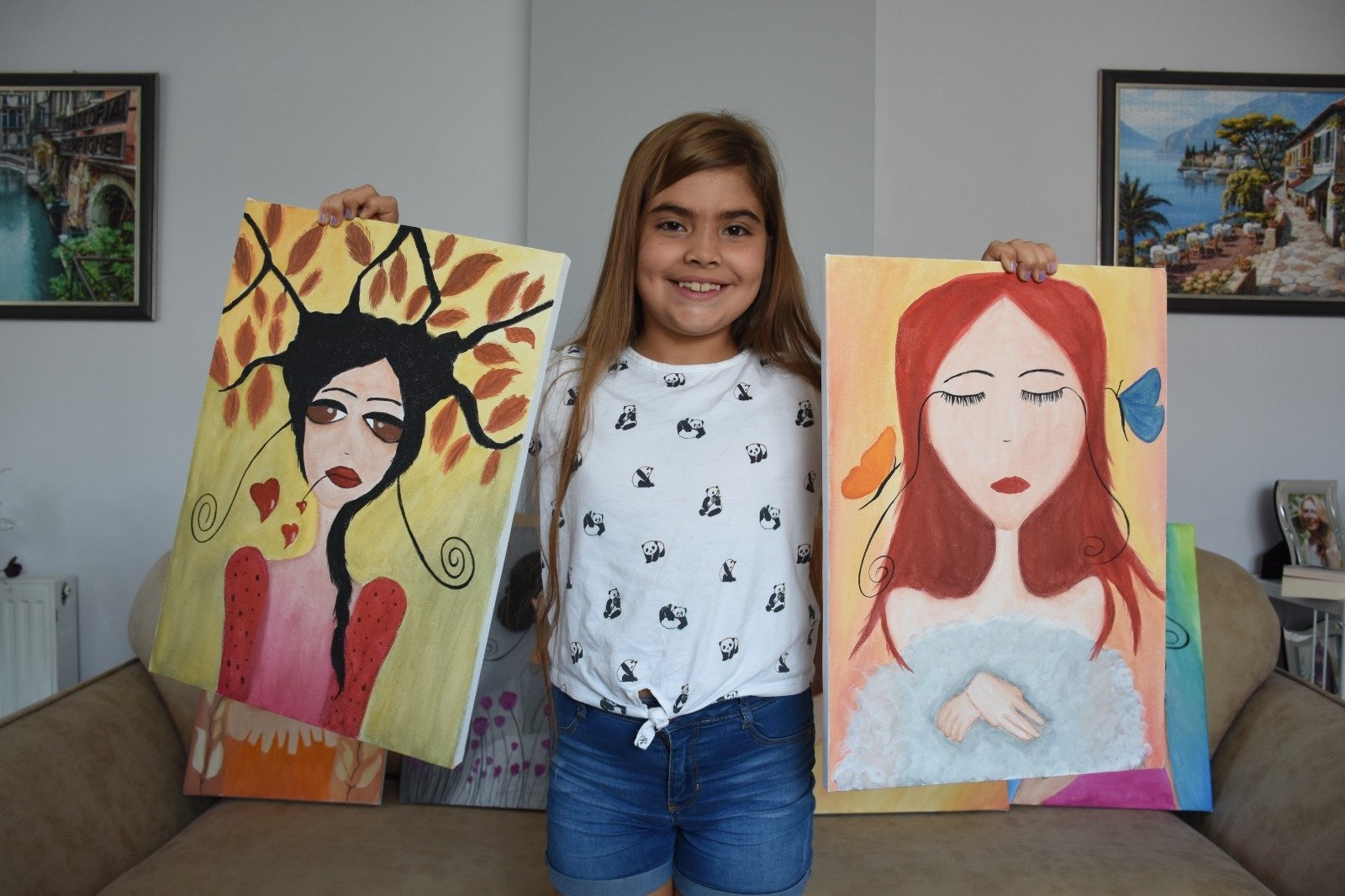 Eight-year-old artist Zeynep Yağmur Çevik poses with two of her paintings in Istanbul, Turkey, Aug. 15, 2022. (AA Photo)