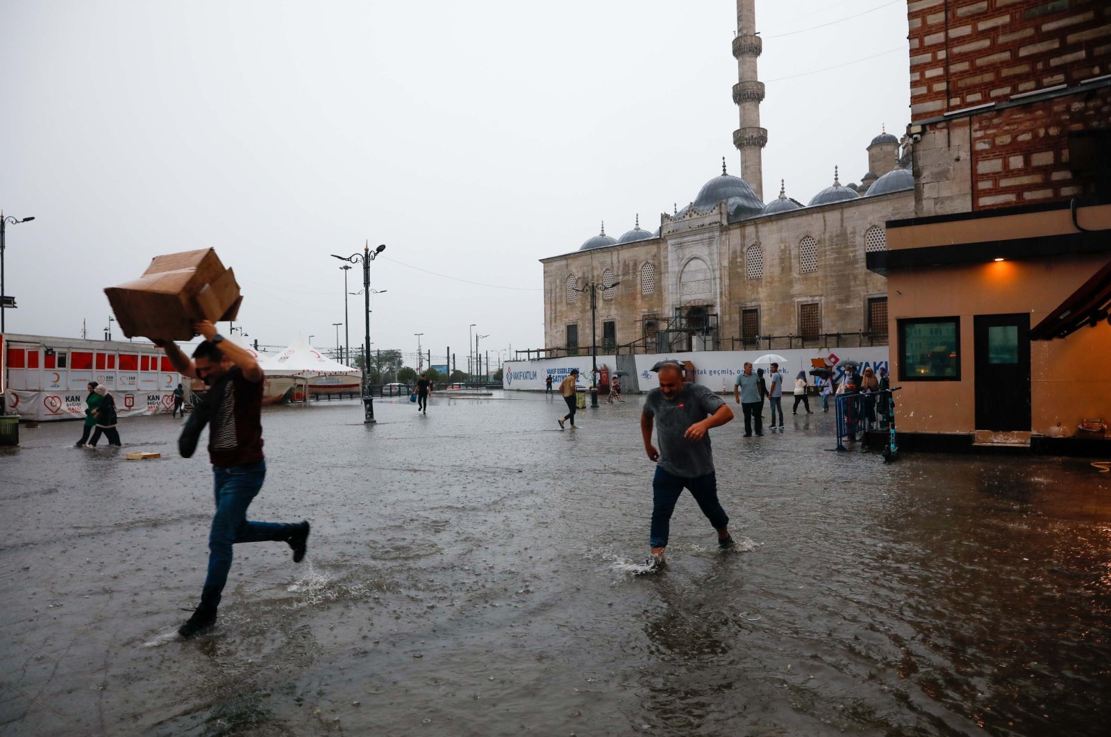 People running on a flooded square, in Istanbul, Türkiye, Aug. 15, 2022. (DHA PHOTO) 