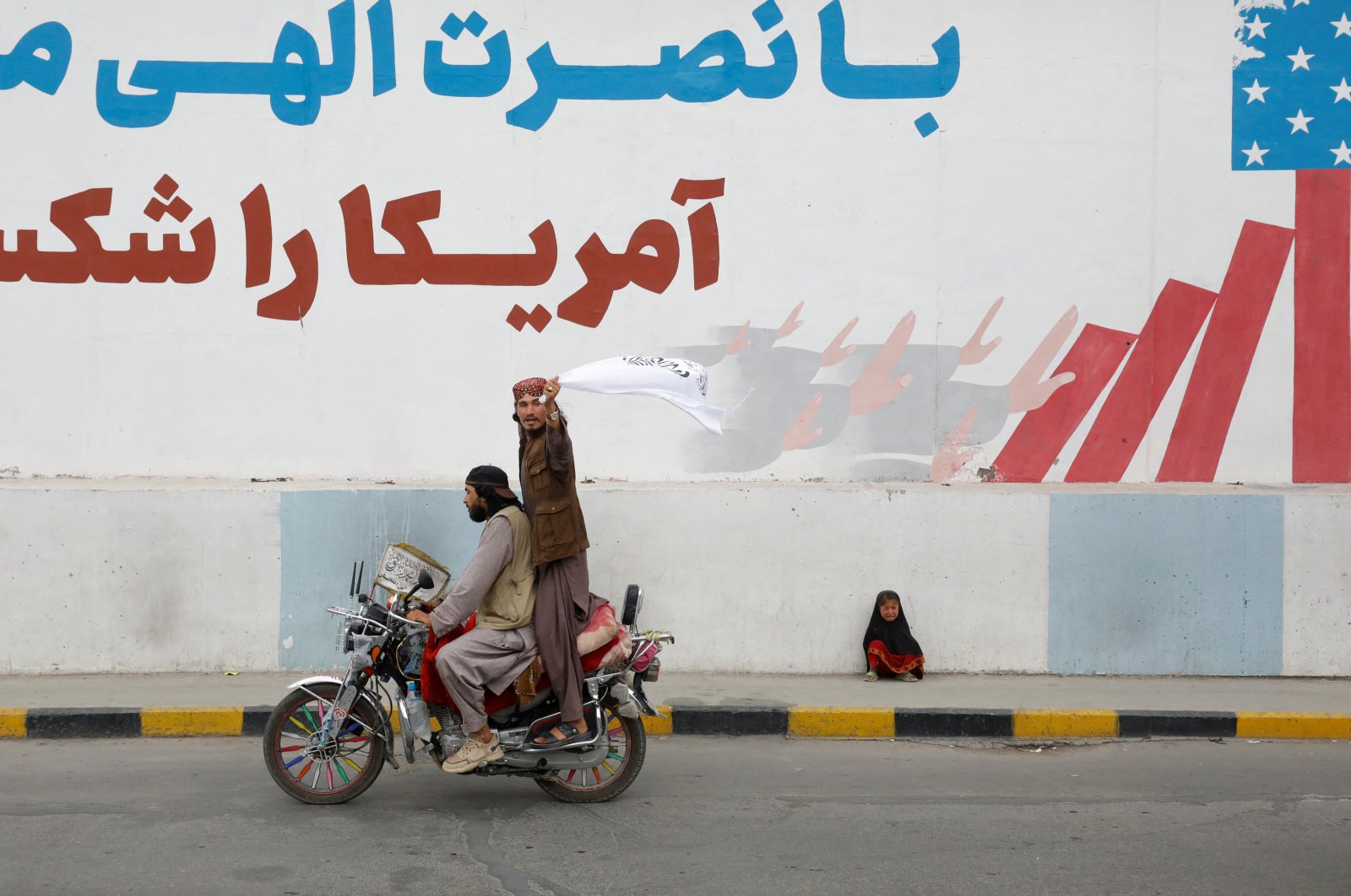 A Taliban supporter holds an Islamic Emirate of Afghanistan flag on the first anniversary of the fall of Kabul on a street in Kabul, Afghanistan, Aug. 15, 2022. (Reuters Photo)