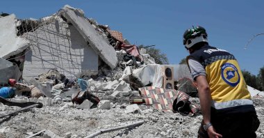 A member of the Syrian civil defense known as the White Helmets walks on the rubble of a house following a Russian airstrike on the outskirts of the opposition-held city of Jisr al-Shughur in Syria&#039;s northwestern province of Idlib, July 22, 2022. (AFP Photo)