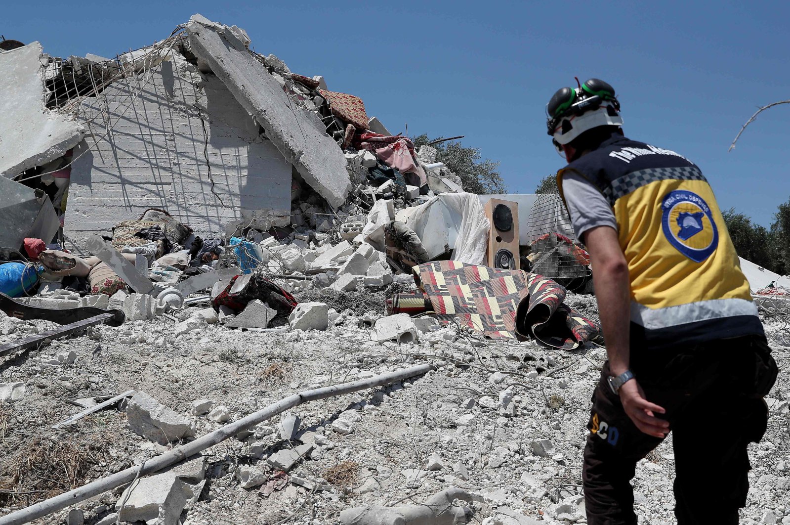 A member of the Syrian civil defense known as the White Helmets walks on the rubble of a house following a Russian airstrike on the outskirts of the opposition-held city of Jisr al-Shughur in Syria&#039;s northwestern province of Idlib, July 22, 2022. (AFP Photo)