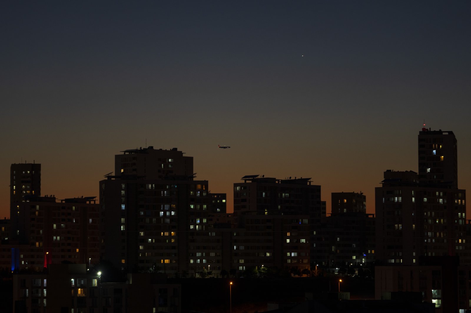 A plane flies over residential buildings during the sunset in Istanbul, Turkey, Aug. 5, 2022. (AP Photo)