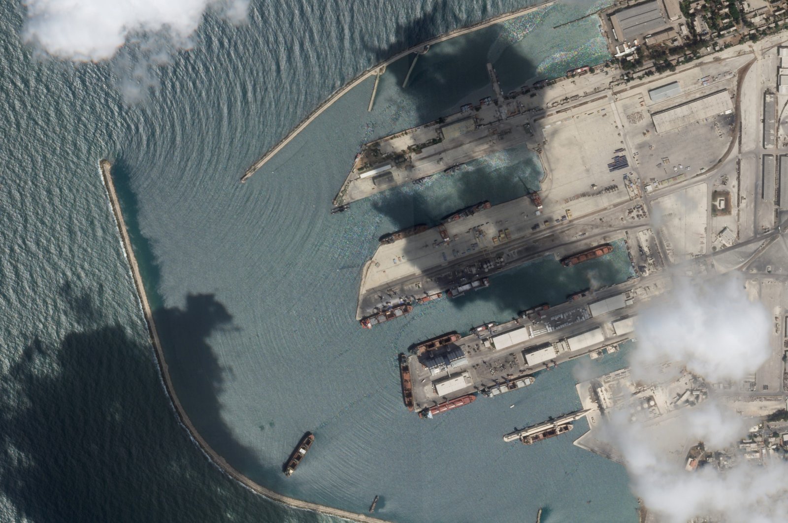 This satellite image from Planet Labs PBC shows the Sierra Leone-flagged cargo ship Razoni, center bottom with four white cranes on its red deck, at port in Tartus, Syria, Aug. 15, 2022. The first shipment of grain to leave Ukraine under a wartime deal has ended up in Syria, even as that country remains a close ally of Moscow, satellite images analyzed Tuesday by The Associated Press show. (Planet Labs PBC via AP)