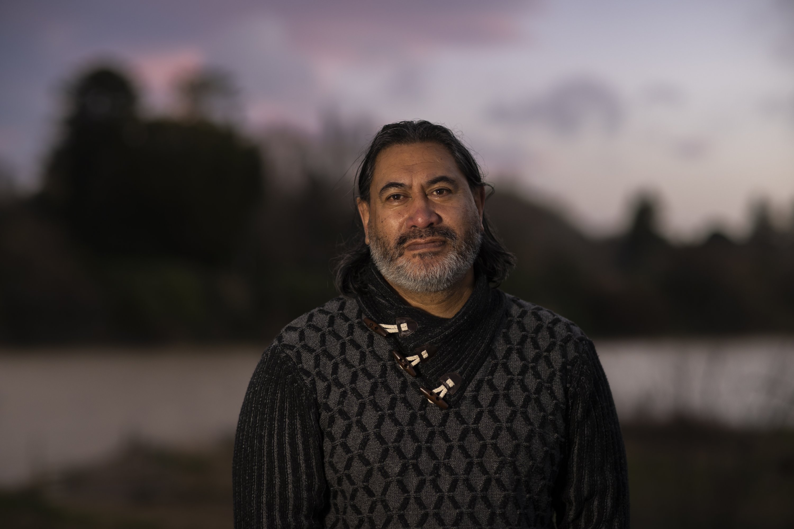 Geoff Hipango, yang mengelola layanan kesehatan mental dan kecanduan untuk penyedia layanan suku di Whanganui dan yang tinggal di komunitas Maori marae, berdiri untuk potret di tepi Sungai Whanganui di Selandia Baru, 15 Juni 2022. (AP Photo)