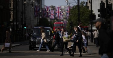 People carrying shopping bags cross the road on Oxford Street in London, U.K., May 18, 2022. (AP Photo)