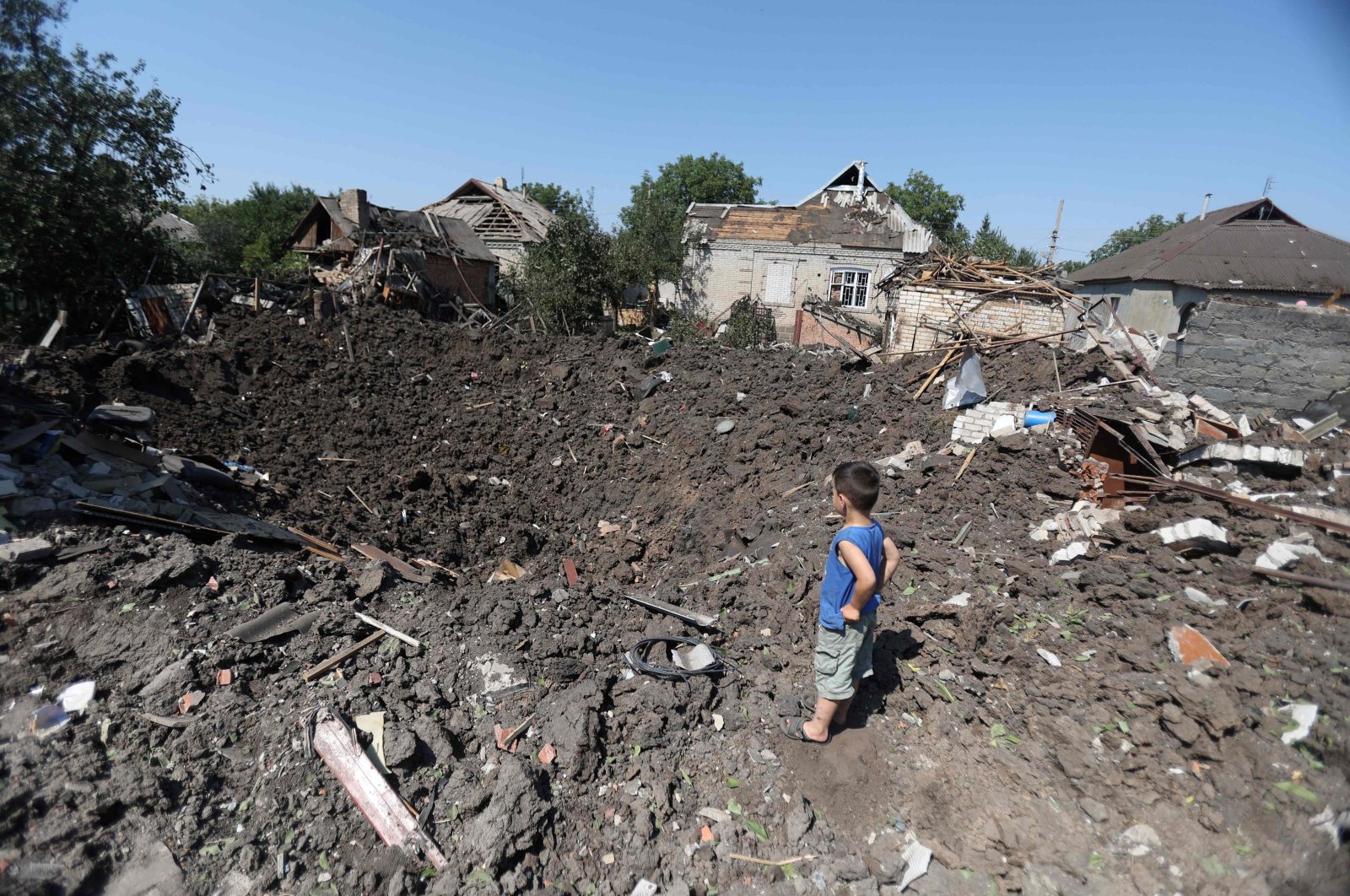 A boy looks at a crater following a strike in the village of Druzhkivka, Donetsk region, Ukraine, Aug. 17, 2022. (AFP Photo)