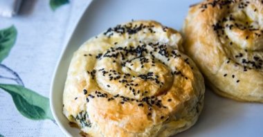 A close up shot of homemade cheese and spinach swirl pastries topped with sesame seeds on a plate. (Getty Images)