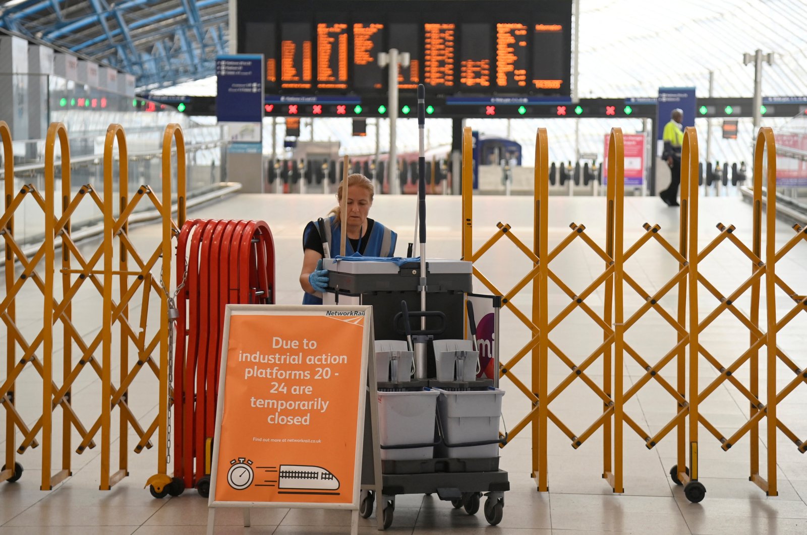A cleaning operative moves past temporary closure barriers as rail workers in Britain strike over pay and terms, at Waterloo Station, in London, Britain, Aug. 18, 2022. (Reuters Photo)