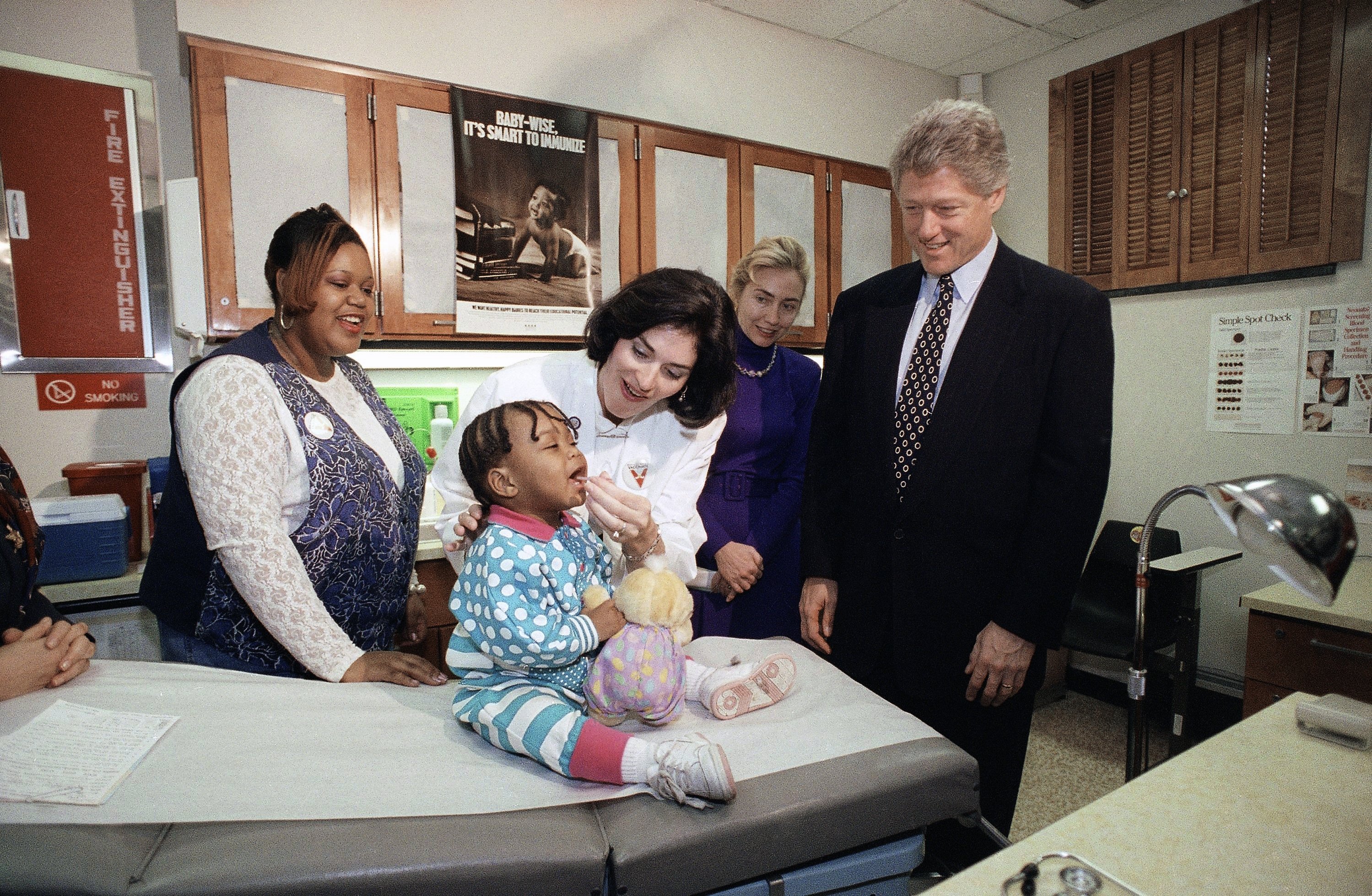 Kemudian Presiden AS Bill Clinton dan Ibu Negara Hillary Rodham Clinton menyaksikan perawat Dorothy Sellers memberikan vaksin polio oral kepada Danielle Bailey yang berusia 20 bulan di sebuah klinik kesehatan Arlington County di Arlington, Virginia, AS, 13 Februari 1993. (AP Foto)