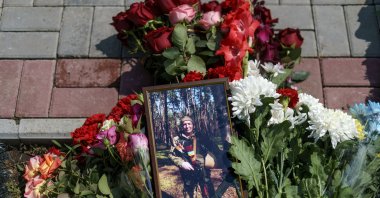 Flowers surround a photo of Oleh Panchenko next to his grave during his burial service in Pokrovsk, Donetsk region, eastern Ukraine, Thursday, Aug. 4, 2022. Panchenko, 48, a Ukrainian soldier, was killed in battle with Russian forces July 27 in the Donetsk region. (AP Photo/David Goldman)