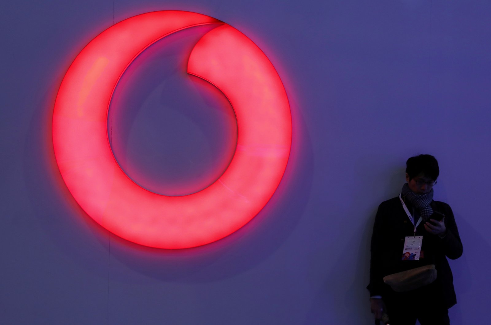 A man checks his mobile phone next to a Vodafone logo at the Mobile World Congress in Barcelona, Spain, Feb. 28, 2018. (REUTERS/Sergio Perez/File Photo)