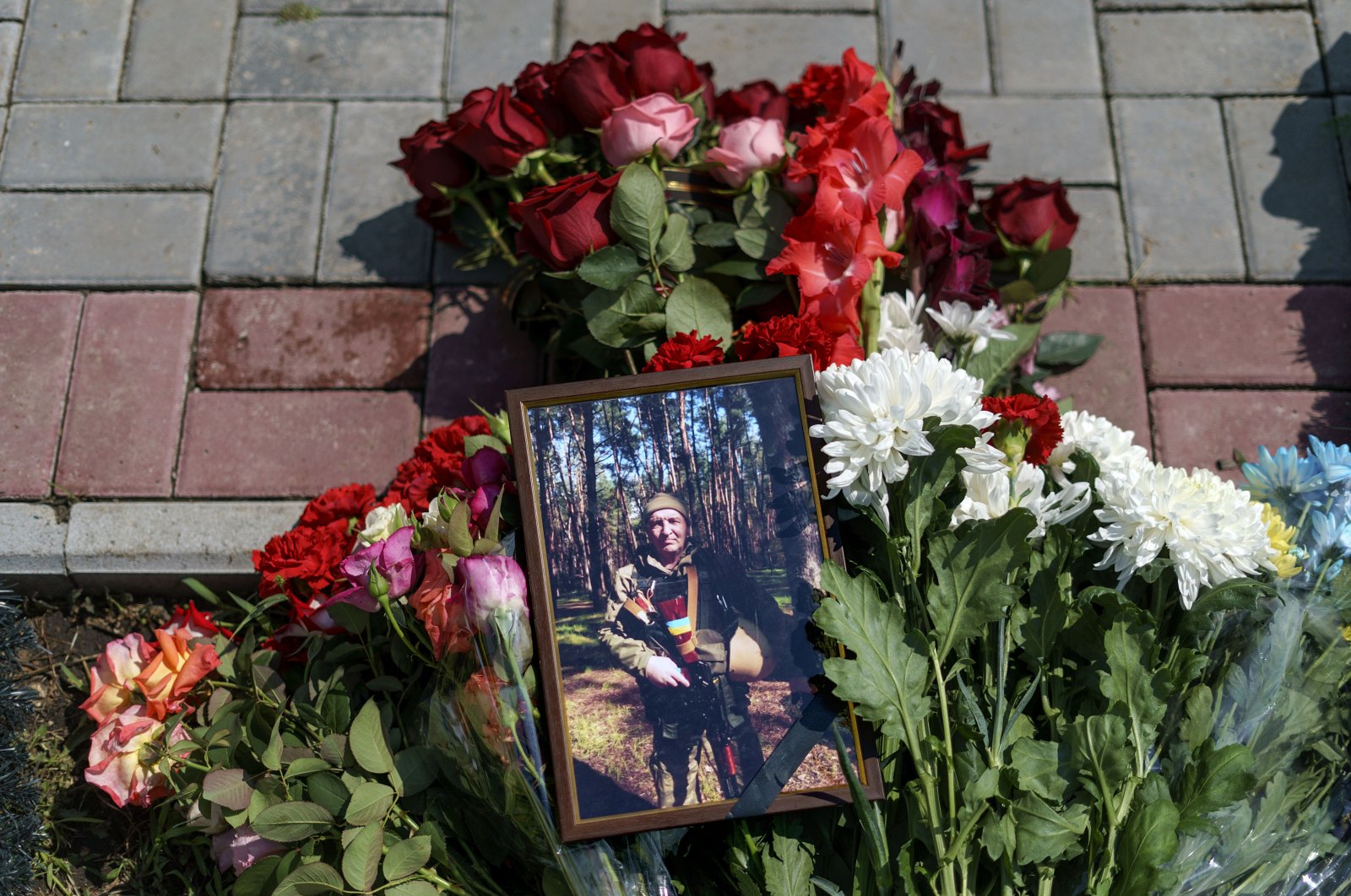 Flowers surround a photo of Oleh Panchenko next to his grave during his burial service in Pokrovsk, Donetsk region, eastern Ukraine, Thursday, Aug. 4, 2022. Panchenko, 48, a Ukrainian soldier, was killed in battle with Russian forces July 27 in the Donetsk region. (AP Photo/David Goldman)