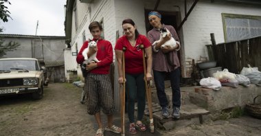 Danyk Rak, 12, his mother Liudmila Koval (C) and grandmother Nina stand in the village of Voznesenske, near Chernihiv, Ukraine, Aug. 13, 2022. (AP Photo)