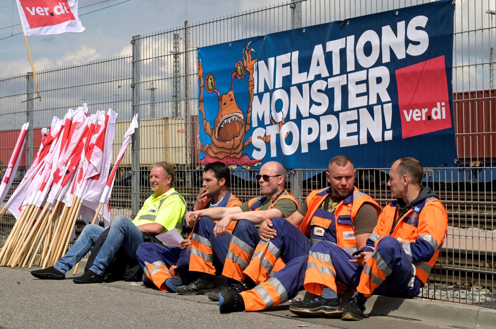 Workers sit in front of a banner reading &quot;Stop the Inflation Monster&quot; at the Burchardkai Container Terminal as they go on strike for higher wages in the harbor in Hamburg, Germany, June 9, 2022. (Reuters Photo)