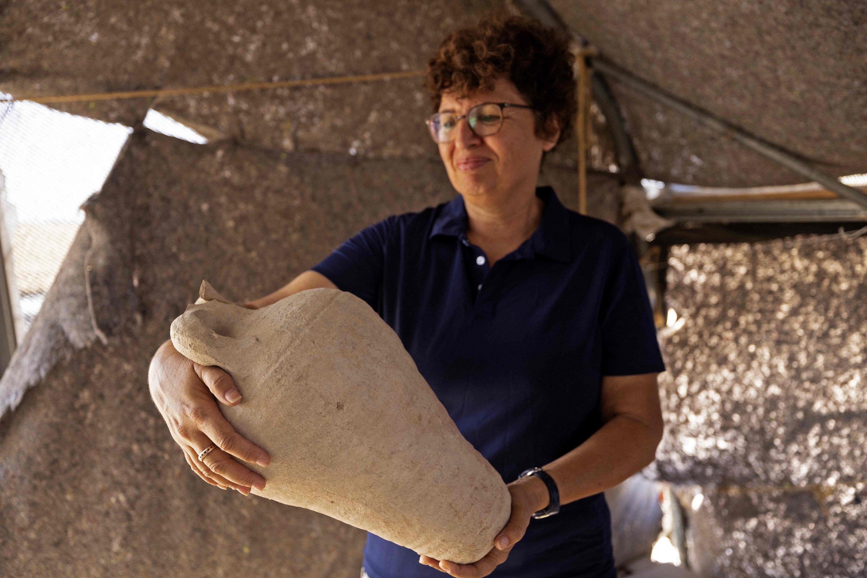 Arkeolog Elena Kogan Zahavi dari Israel's Antiquities Authority menampilkan artefak yang ditemukan dari sebuah rumah besar yang berasal dari periode awal Islam antara abad kedelapan dan kesembilan, di kota Badui Rahat di gurun Negev selatan Israel, 23 Agustus 2022. (AFP Photo )