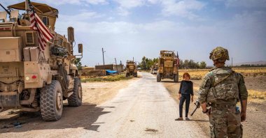 A U.S. soldier stands near a child during a patrol near the Syrian-Turkish border in one of the villages that was subject to bombardment the previous week in the countryside east of Qamishli, Hassakeh province, northeastern Syria, Aug. 21, 2022. (AFP Photo)