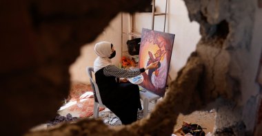 A Palestinian artist draws a painting inside the damaged house of Gaza artist Duniana Al-Amour, who had been killed during the Israel-Gaza fighting earlier this month, in the Gaza Strip, Palestine, Aug. 23, 2022. (Reuters Photo)