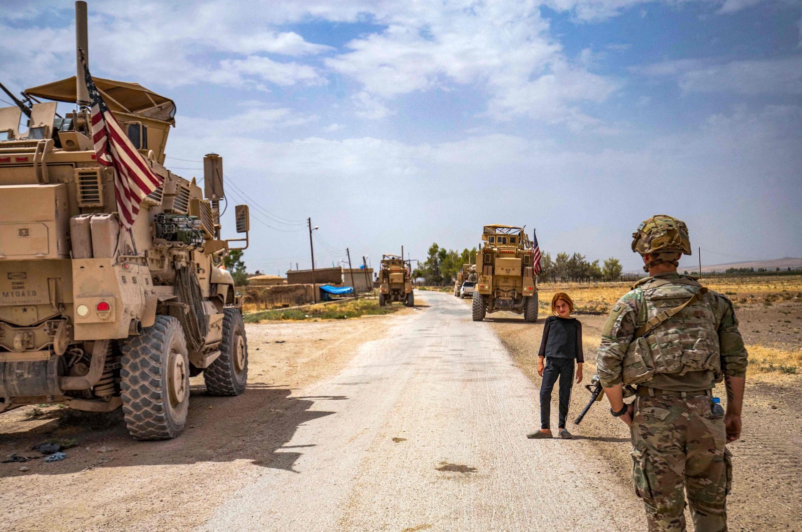 A U.S. soldier stands near a child during a patrol near the Syrian-Turkish border in one of the villages that was subject to bombardment the previous week in the countryside east of Qamishli, Hassakeh province, northeastern Syria, Aug. 21, 2022. (AFP Photo)