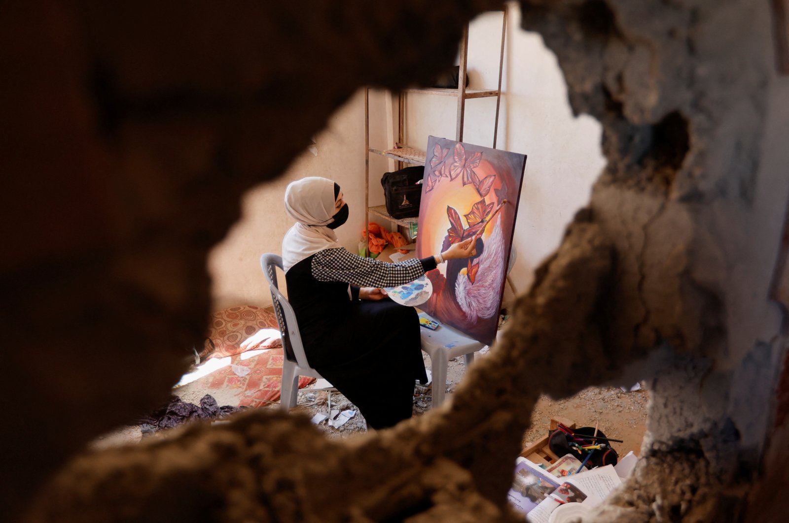 A Palestinian artist draws a painting inside the damaged house of Gaza artist Duniana Al-Amour, who had been killed during the Israel-Gaza fighting earlier this month, in the Gaza Strip, Palestine, Aug. 23, 2022. (Reuters Photo)
