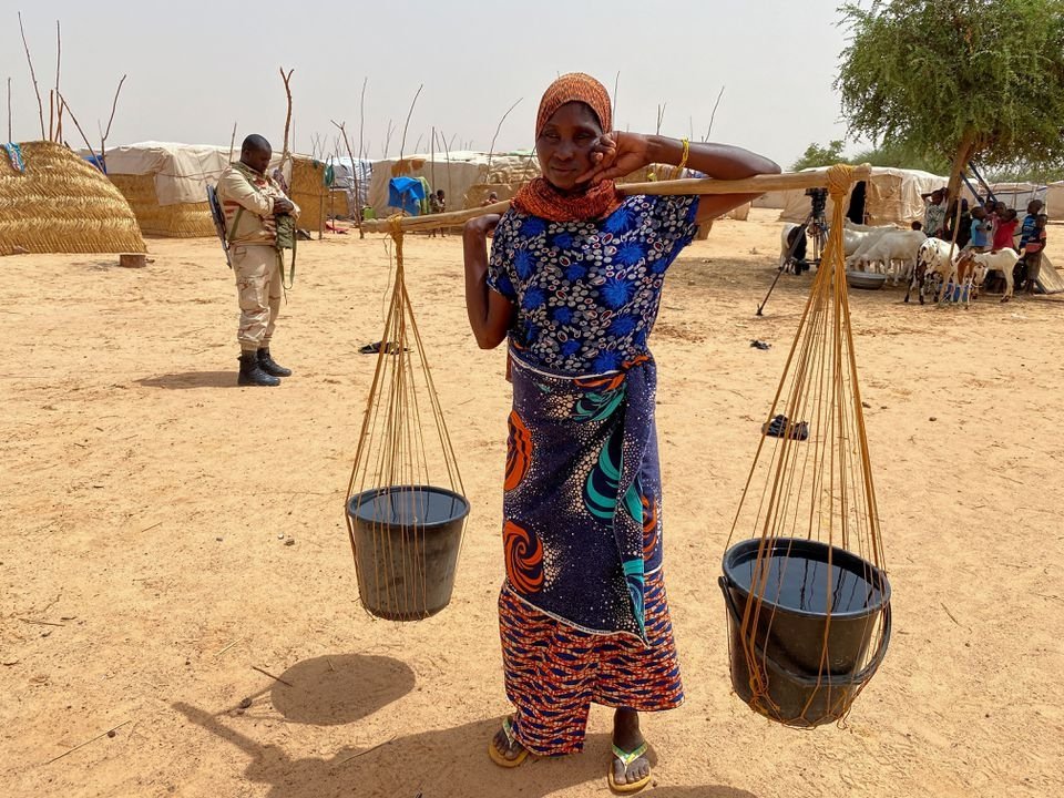 A woman carrying water poses for a photo in a camp for displaced people in the town of Ouallam, Niger, July 6, 2021. (Reuters Photo)