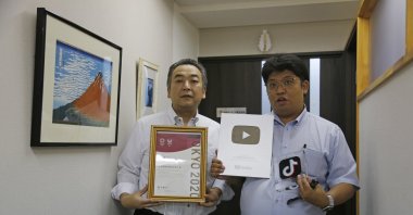 Daikyo Security Chief Executive Daisuke Sakurai (R), and General Manager Tomohiko Kojima hold the awards they have won recently for their Tik Tok videos in the hallway of their Tokyo headquarters office of Daikyo Security Co. Tokyo, Japan, Aug. 22, 2022. (AP Photo)