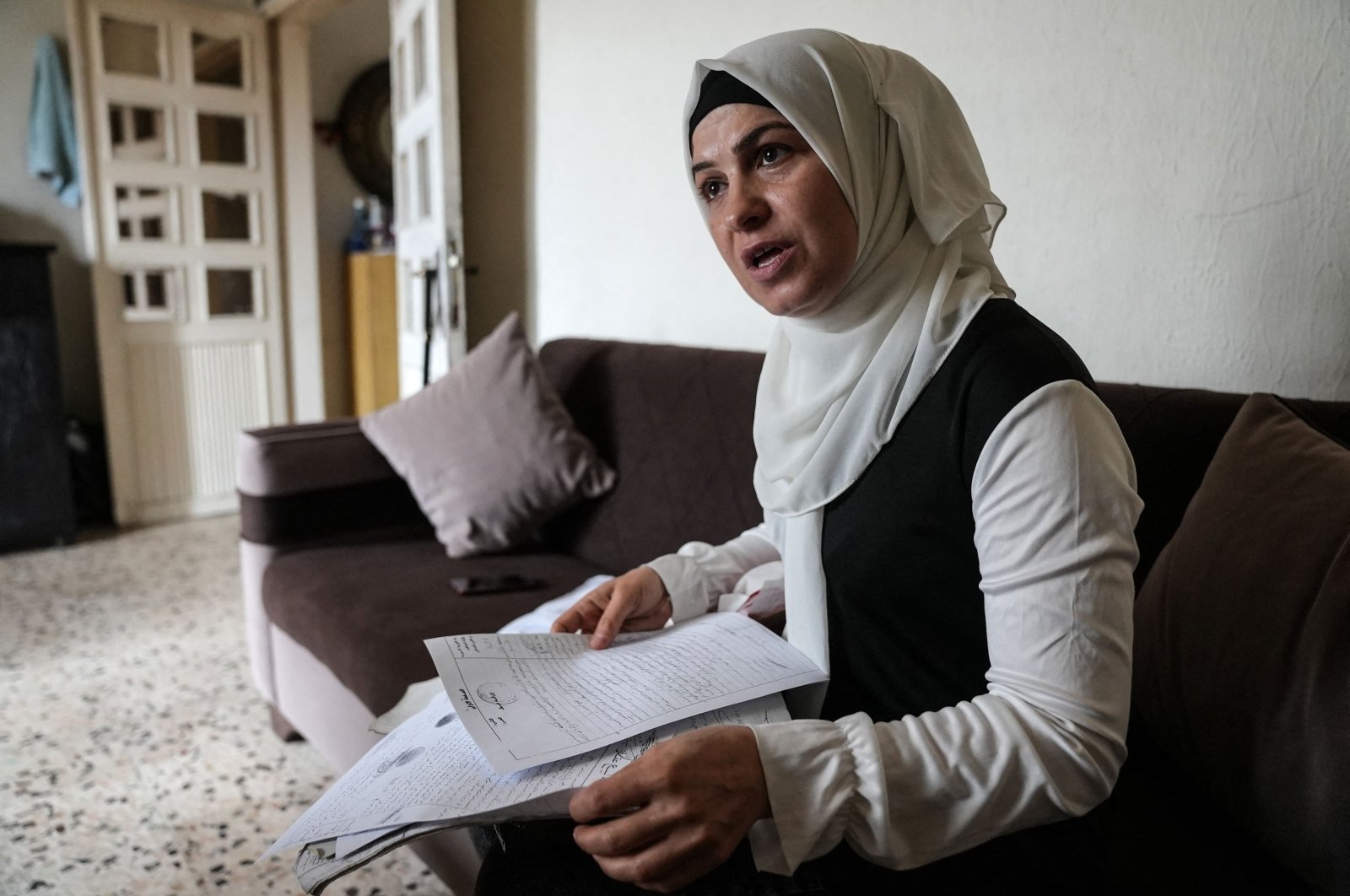 Syrian refugee Ramya al-Sous inspects her family documents at her apartment in Lebanon&#039;s Bekaa Valley, June 13, 2022. (AFP Photo)