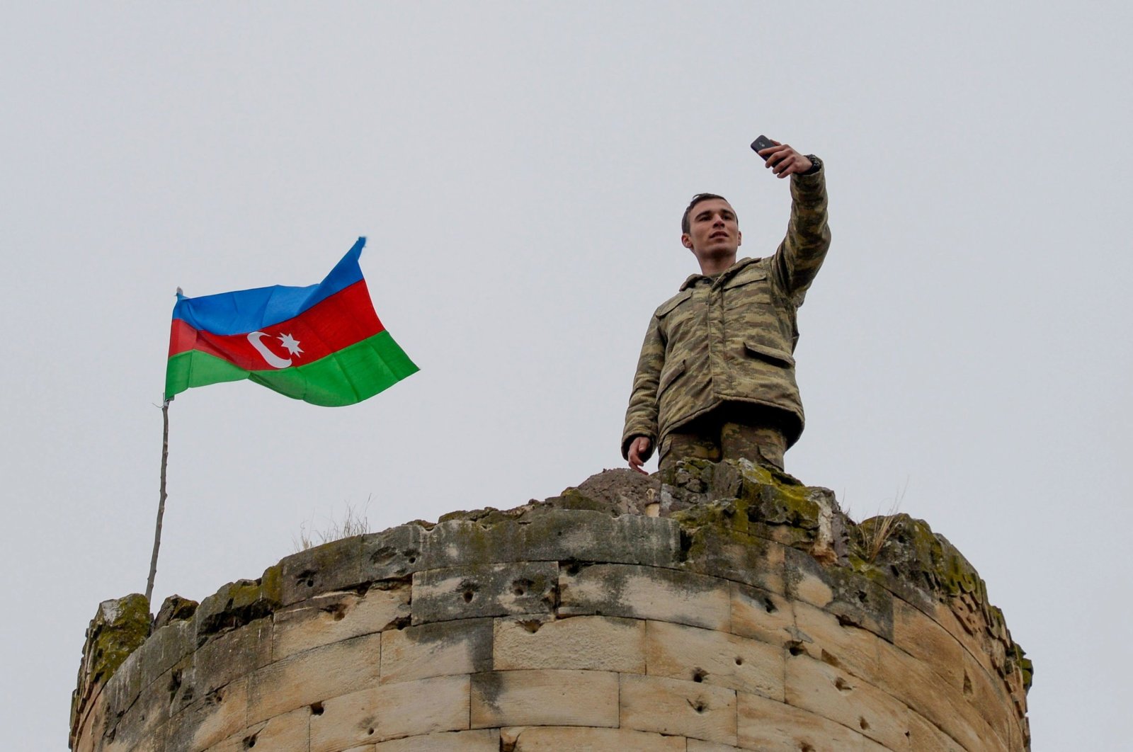 An Azerbaijani soldier takes a selfie with Azerbaijan&#039;s national flag on the top of a tower outside the town of Fuzuli, Karabakh, Azerbaijan, Nov. 26, 2020. (AFP Photo)