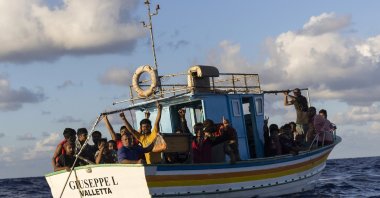 A group of migrants sit in a wooden boat during a rescue operation by NGOs SOS Mediterranee and the International Federation of Red Cross (IFCR), Aug. 25, 2022. (AP Photo)