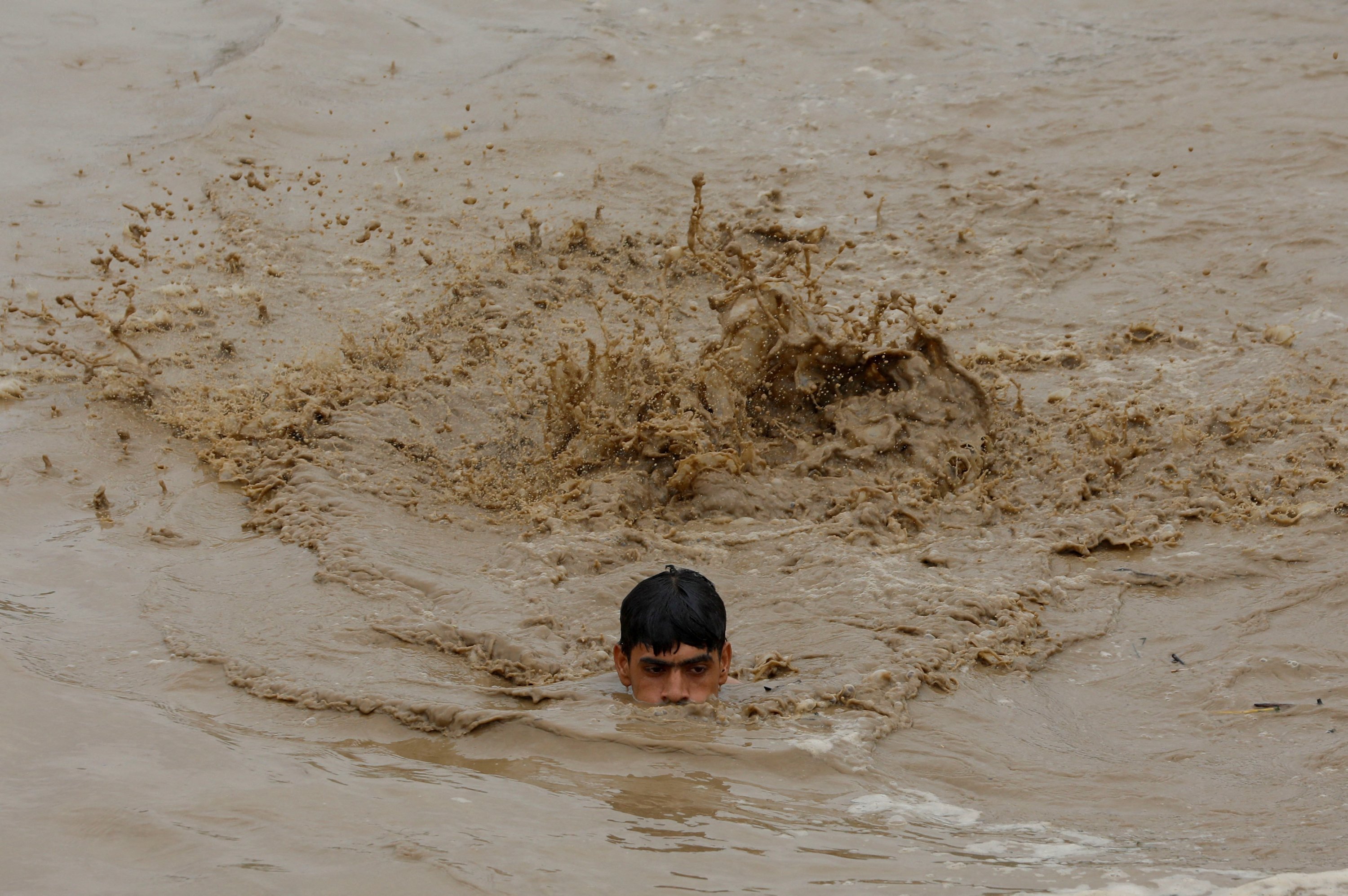 Seorang pria berenang di air banjir saat menuju tempat yang lebih tinggi, Charsadda, Pakistan, 27 Agustus 2022. (Foto Reuters)