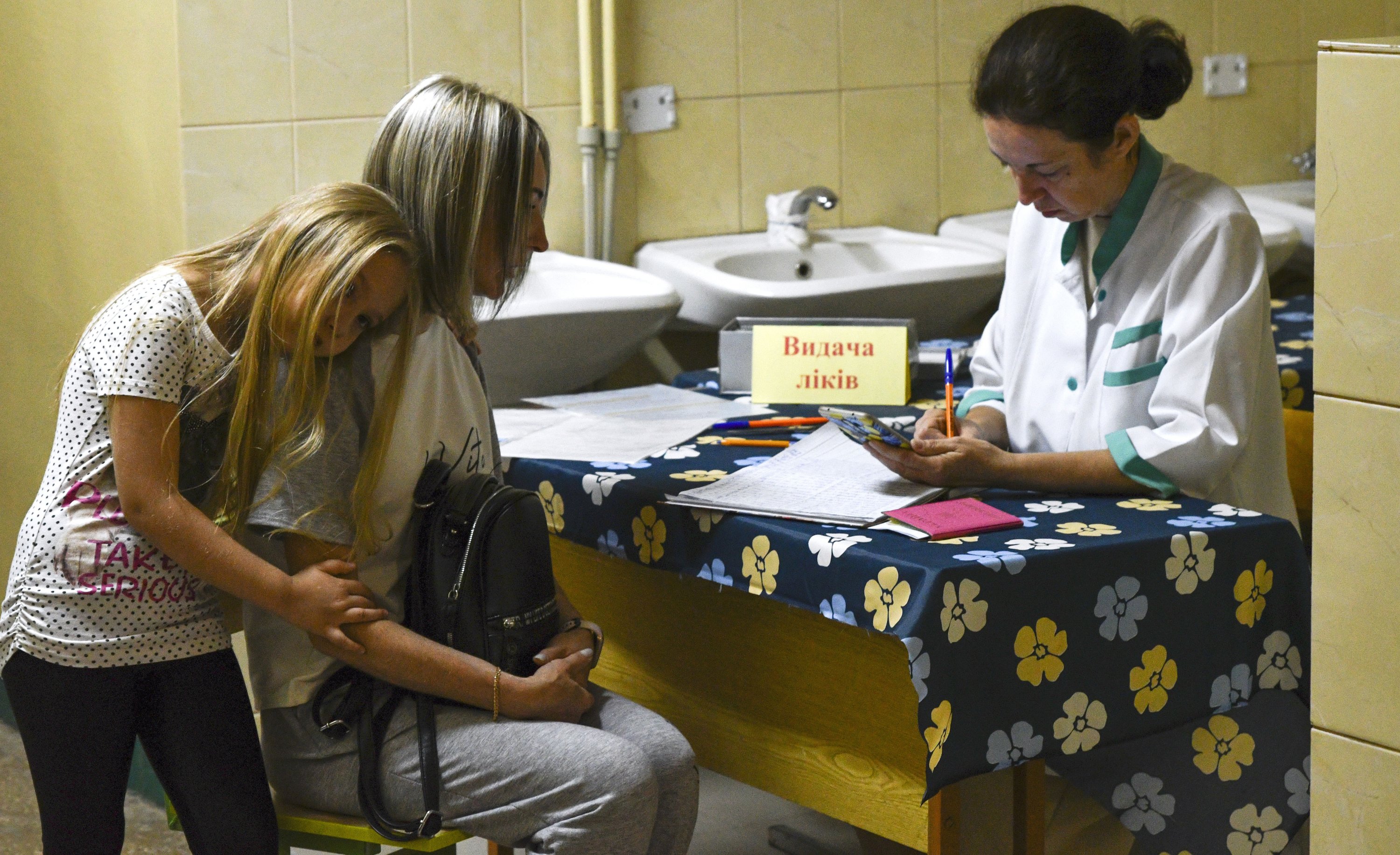 Orang-orang menerima tablet yang mengandung yodium, untuk digunakan jika terjadi kebocoran radiasi, di titik distribusi di Zaporizhzhia, Ukraina, 26 Agustus 2022. (AP Photo)
