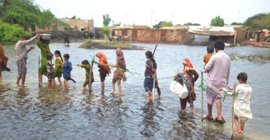 People wade through a flooded area following heavy rains in Sanghar District, Sindh province, Pakistan, Aug. 28, 2022. (EPA-EFE Photo)