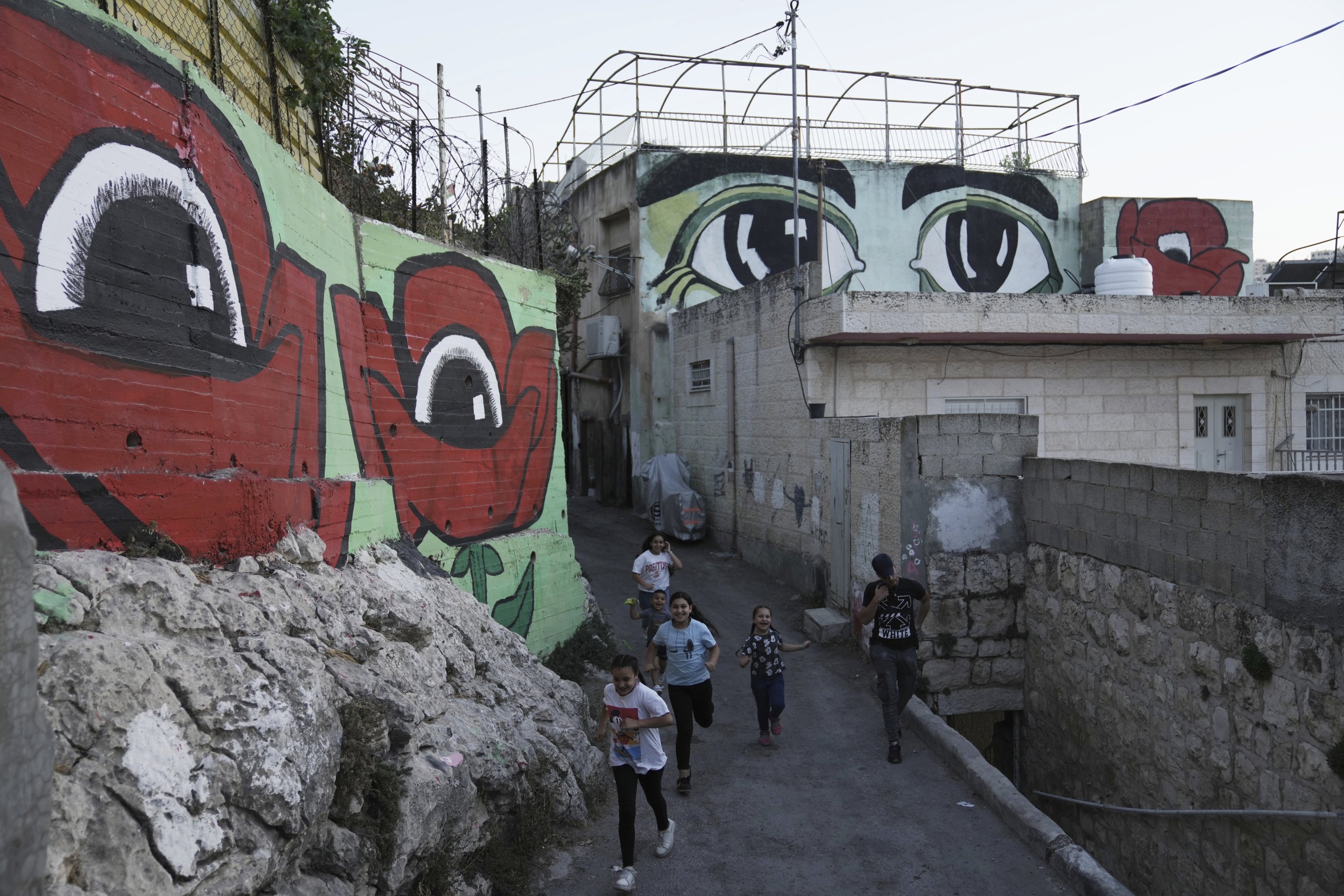 Anak-anak Palestina berjalan di antara mural yang merupakan bagian dari proyek seni publik 