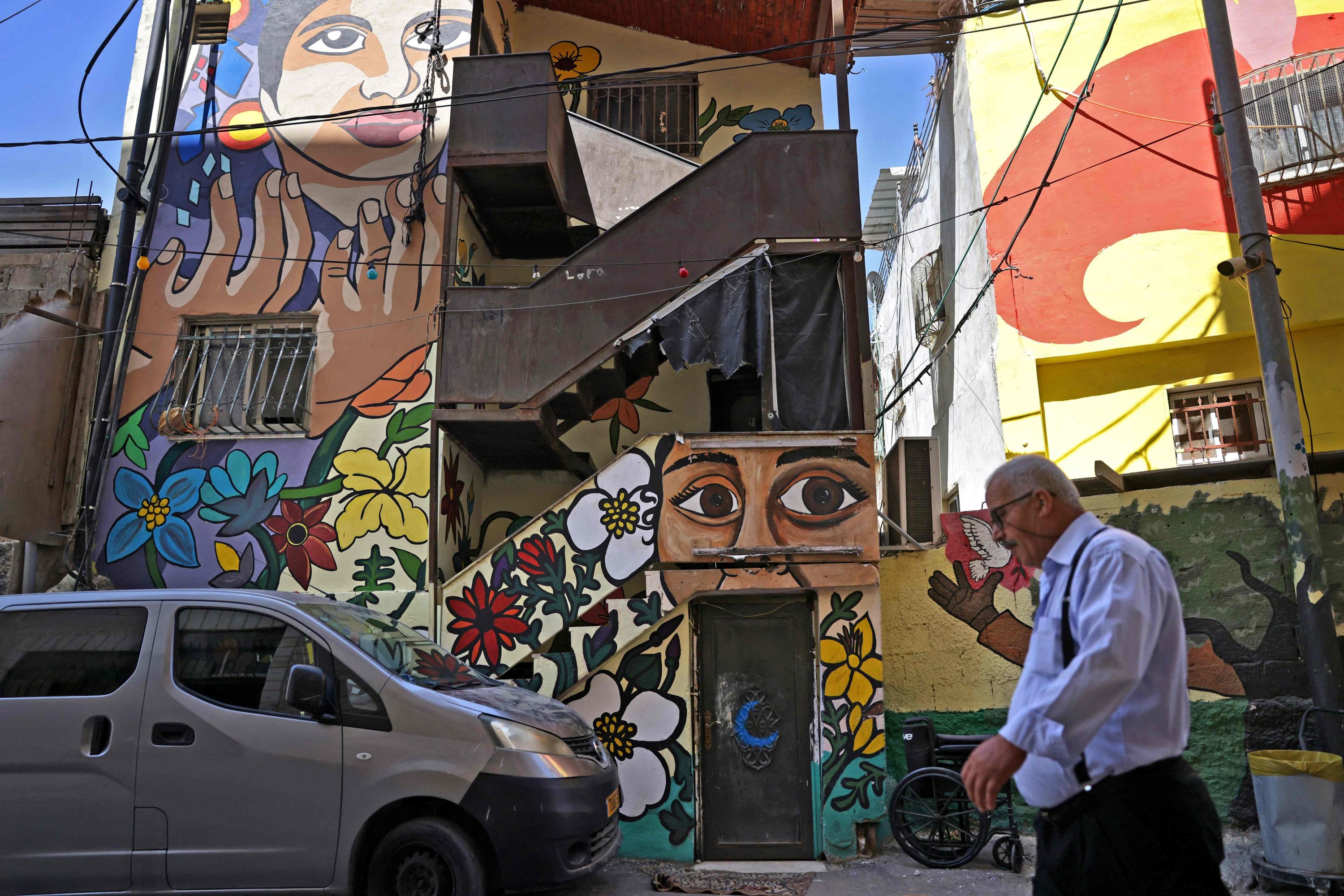 Seorang pria berjalan melewati mural di depan rumah keluarga al-Rajabi, yang dilukis sebagai bagian dari proyek seni publik berjudul 