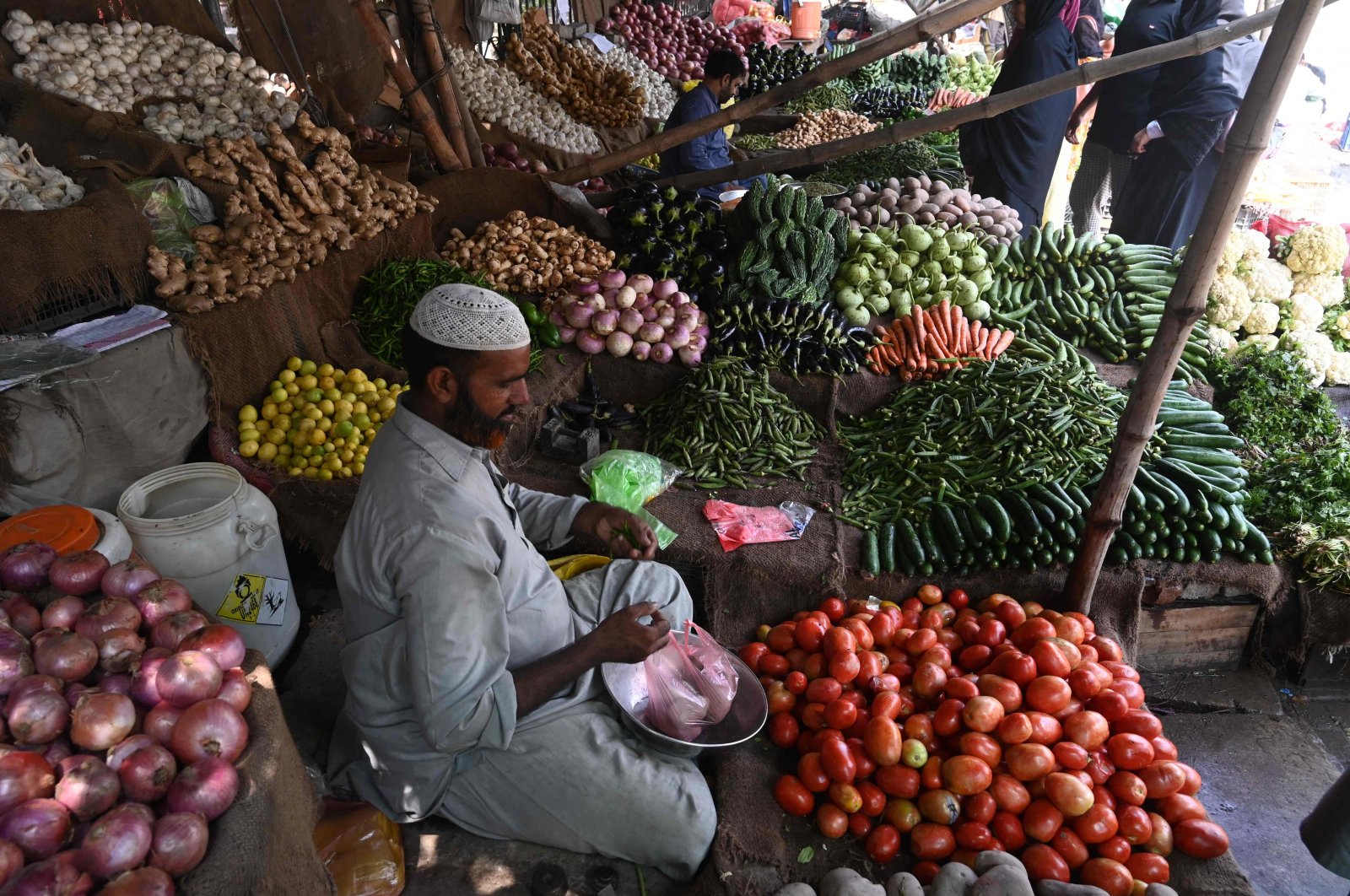 A vendor weighs vegetables for a customer at a local market in Lahore, Pakistan, Aug. 29, 2022. (AFP Photo)